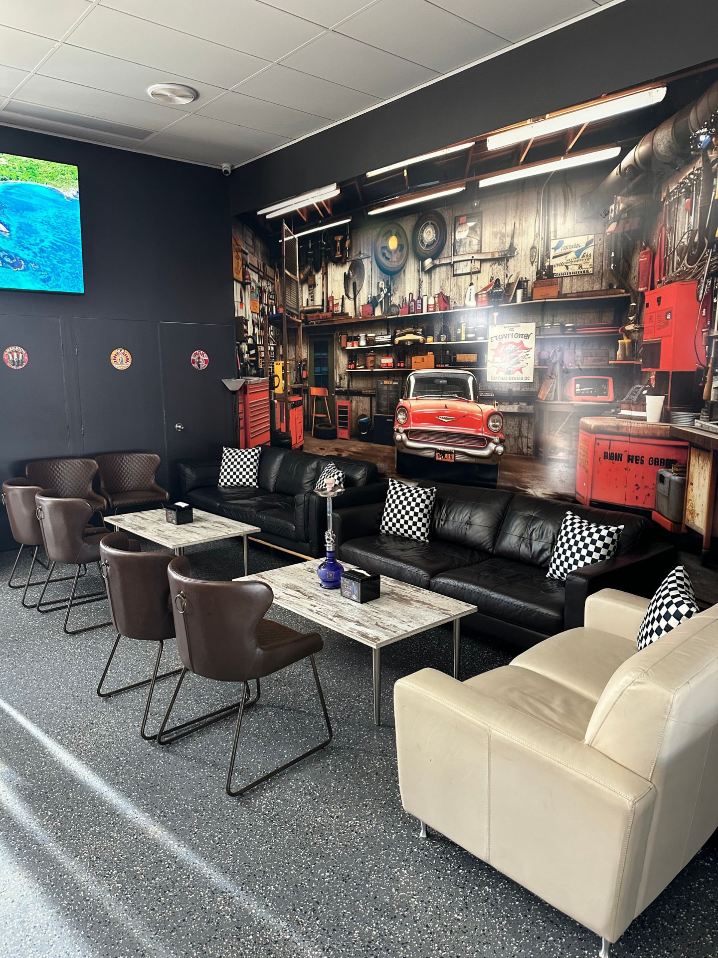 Leather lounges with checkered cushions in front of a vintage garage mural