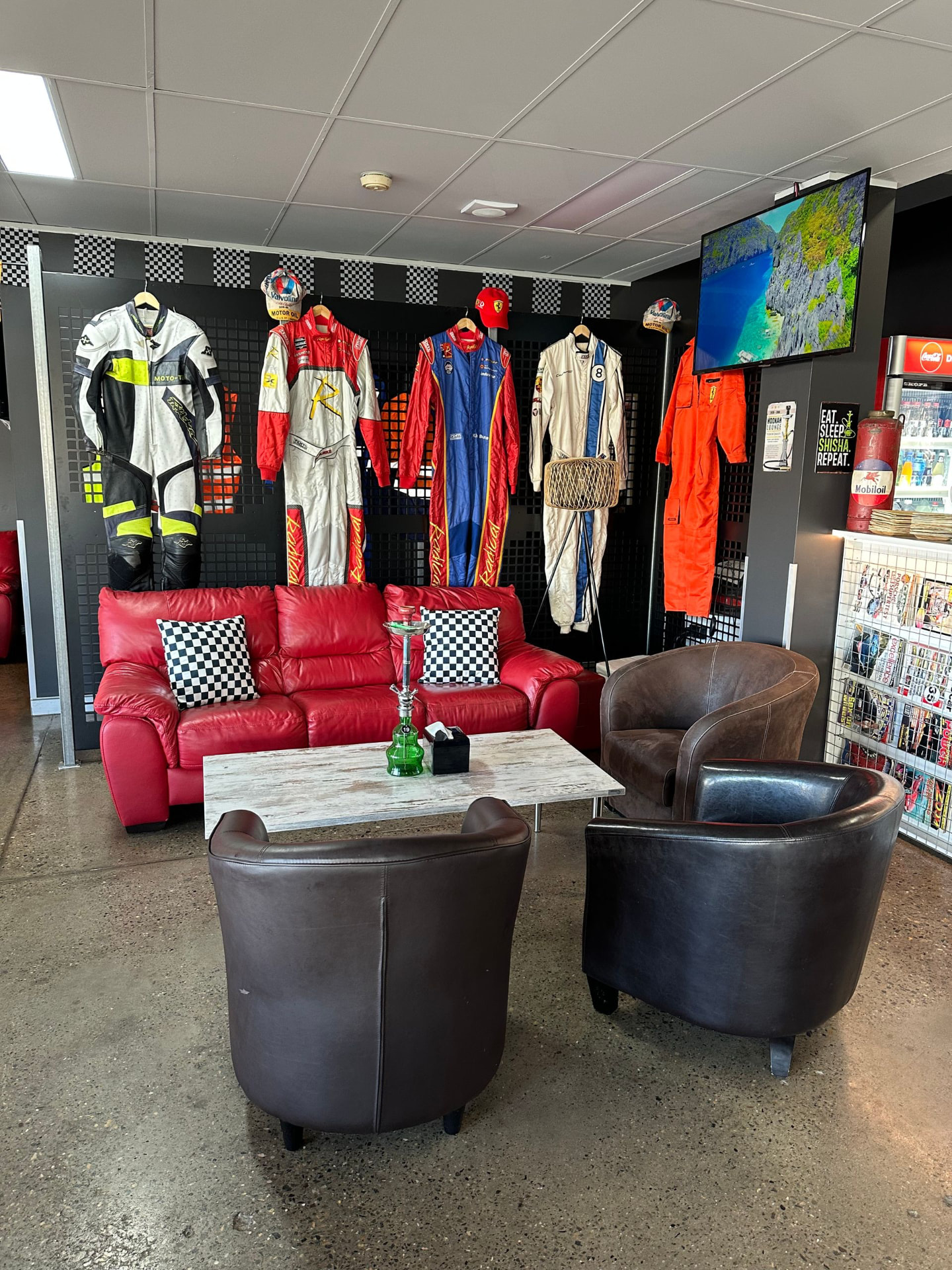 Red leather lounge beneath a wall of racing suits