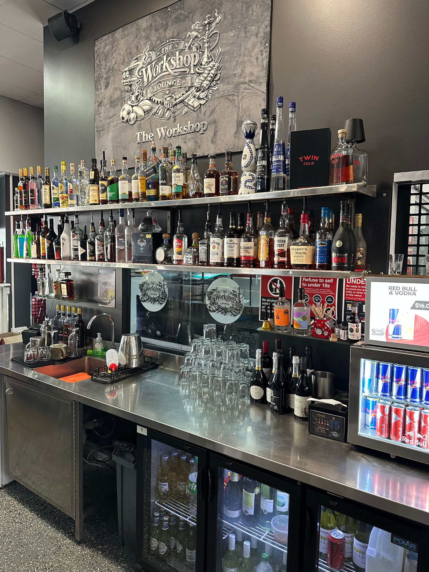 The Workshop bar with top shelf spirits under the Workshop Lounge sign
