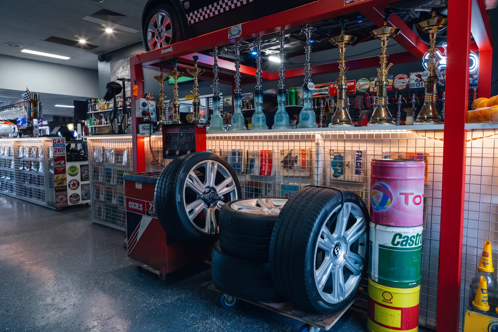 Shishas lined up on the shelf under the black Mini Cooper beside the tyre display